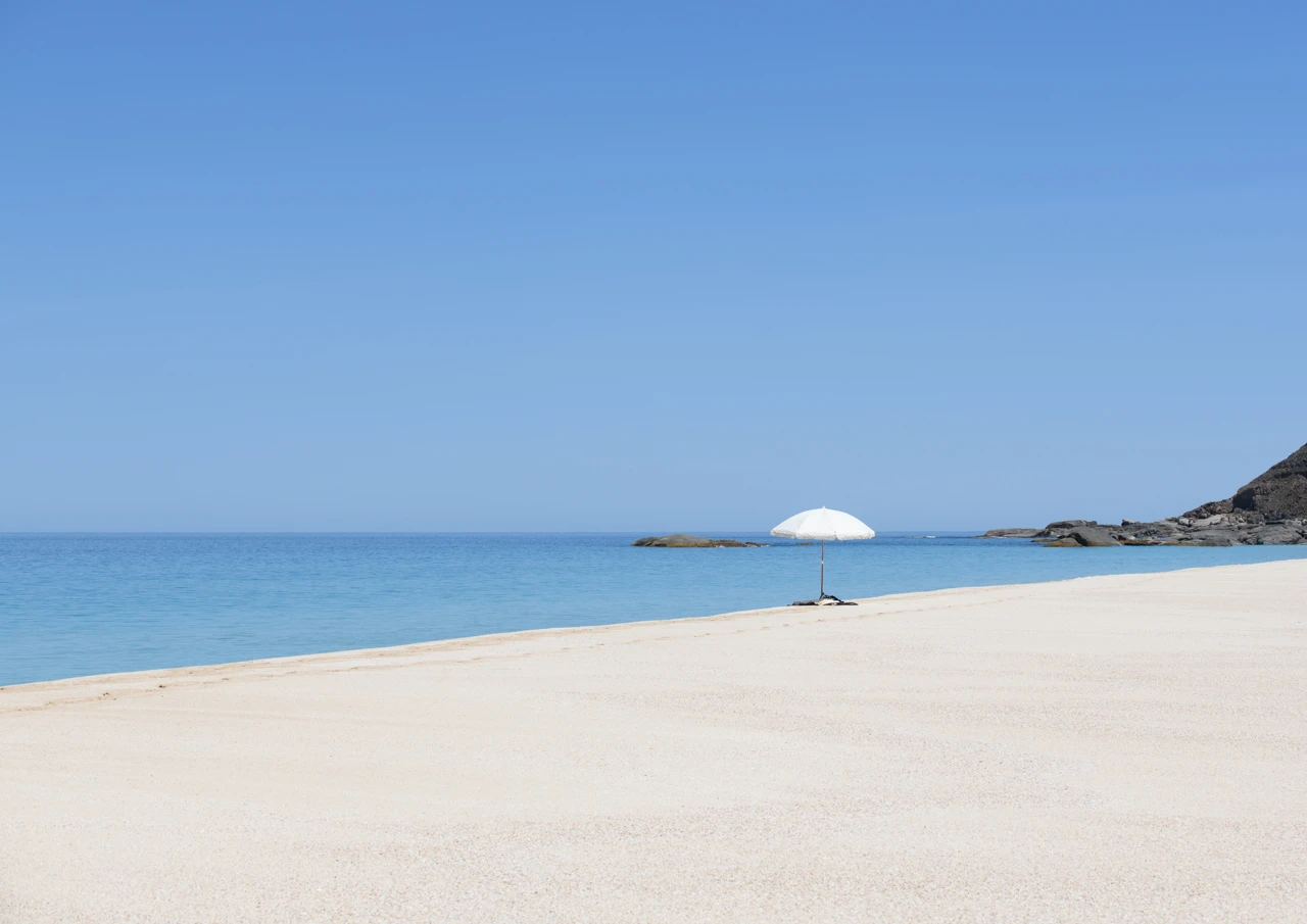 White sun umbrella looking out from West Cape beach Isolated beach with white umbrella
