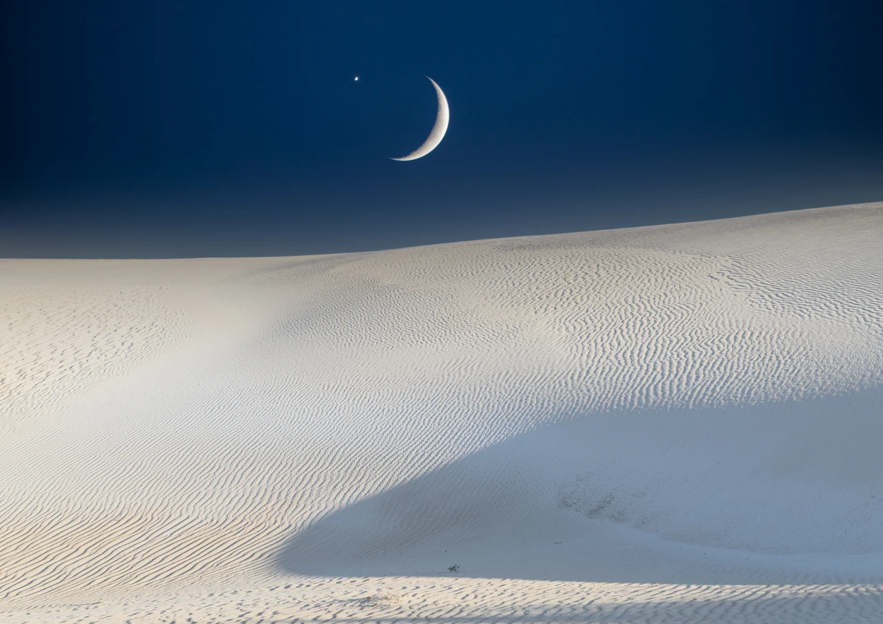 Moon and planet over sand hills