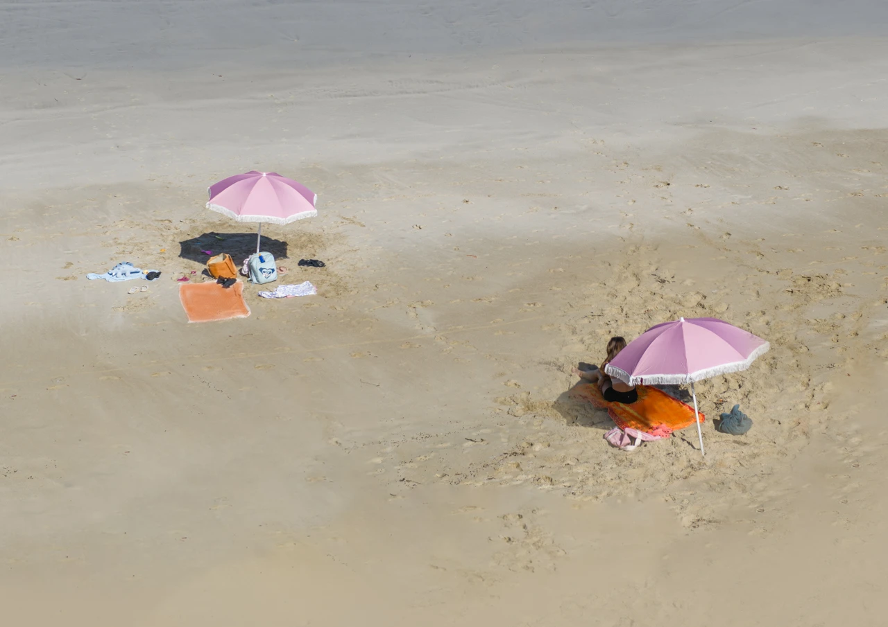 Sandy beach and two pink sun umbrellas