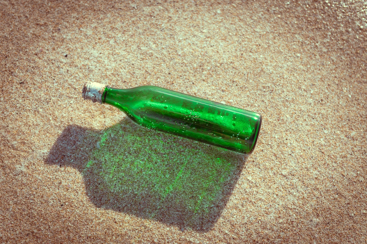 Green bottle found washed up on the sandy shore