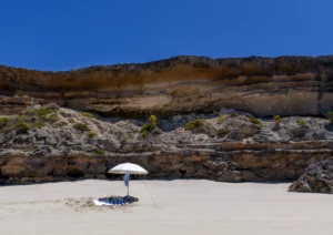 Beach and cliffs with sun umbrella in the foreground