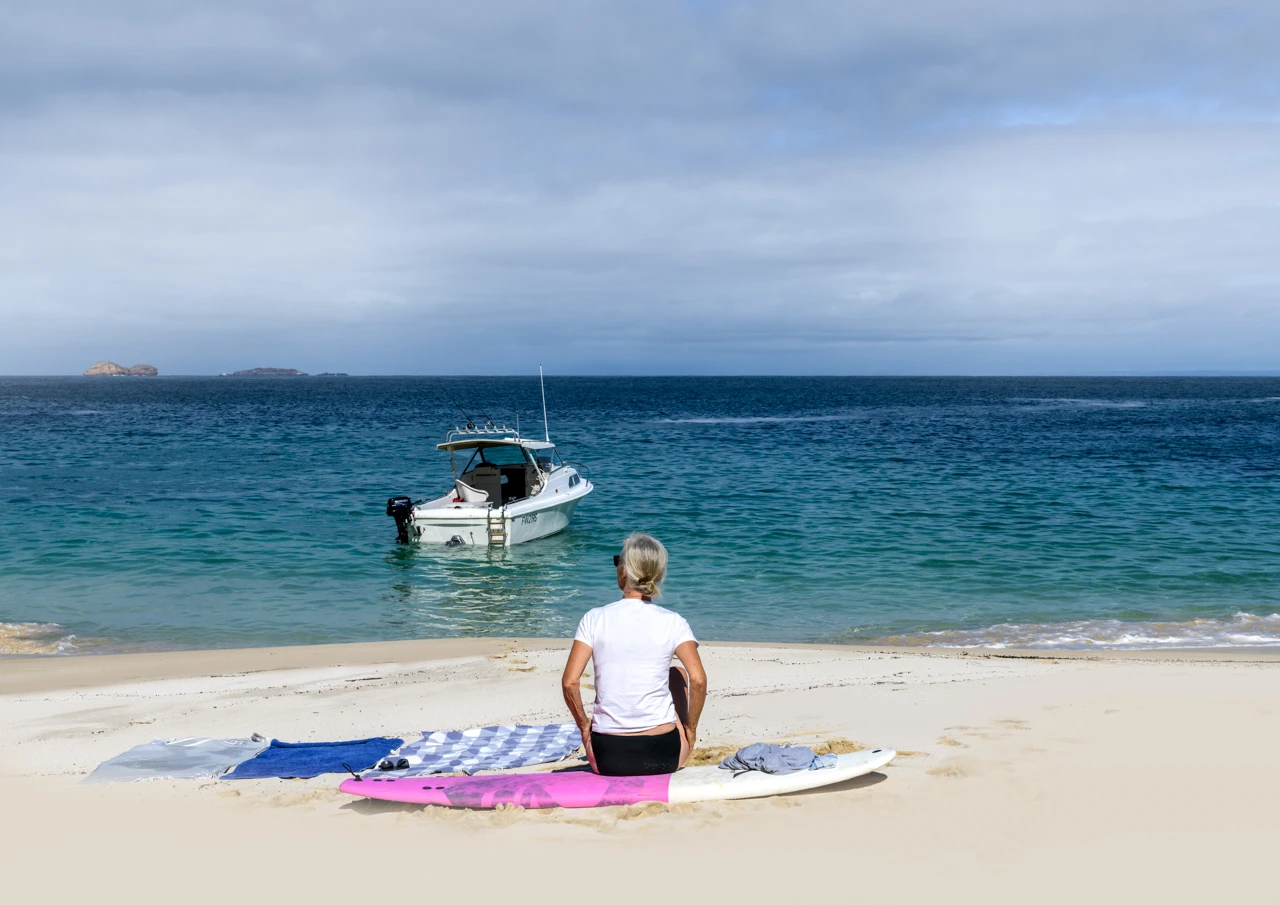 Wendy Philip sitting on a surfboard at Wilder beach Yorke Peninsula