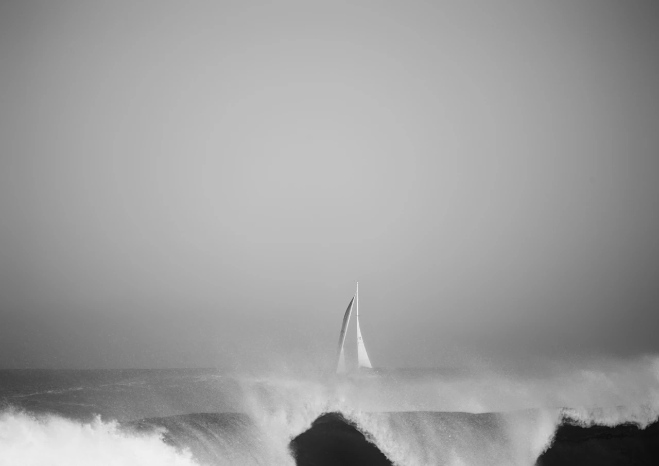 White sail as a wave on the shore breaks